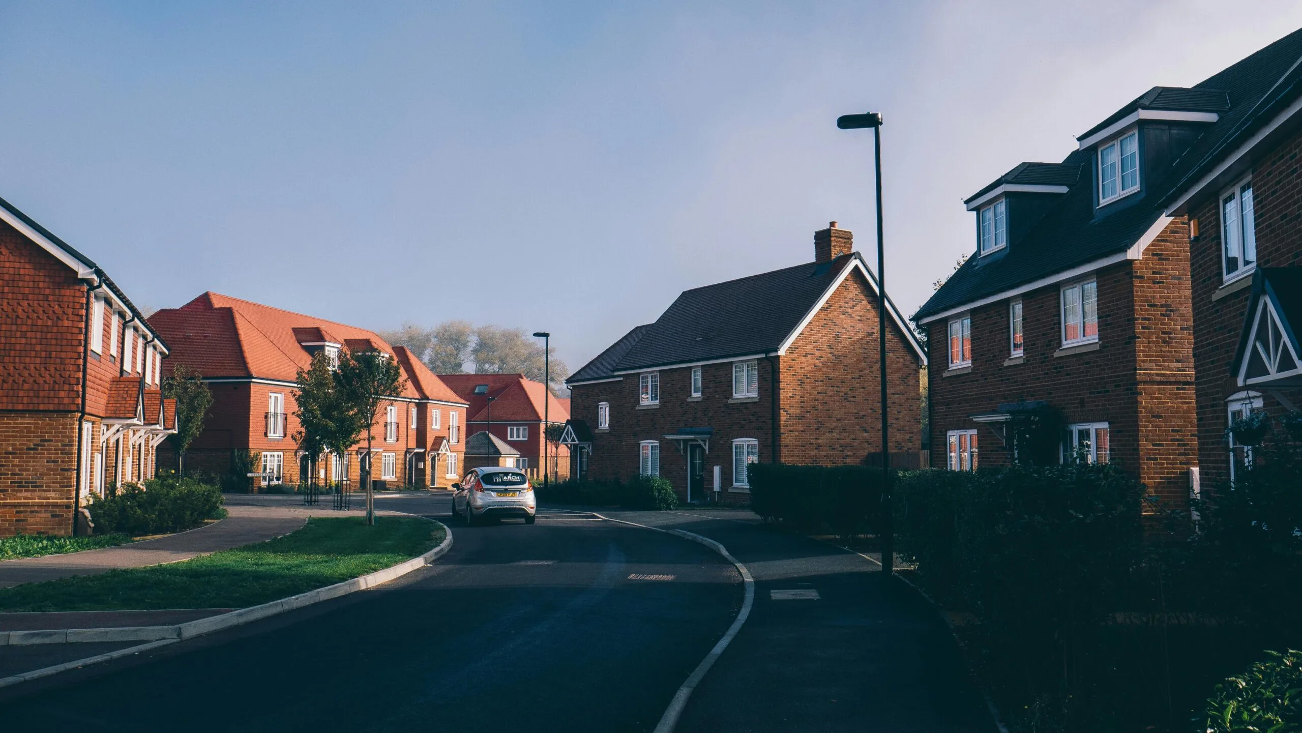 Residential street with brick houses and a clear sky representing the real estate industry